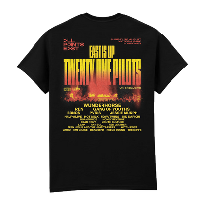 PRE-ORDER: All Points East 2026 Twenty One Pilots Event T-Shirt by All Points East—a black tee with “EAST IS UP TWENTY ONE PILOTS” printed in yellow and red on the front, available at the main merchandise stand. The back features the festival lineup and details in yellow and white text, set against a backdrop of city and fire graphics.